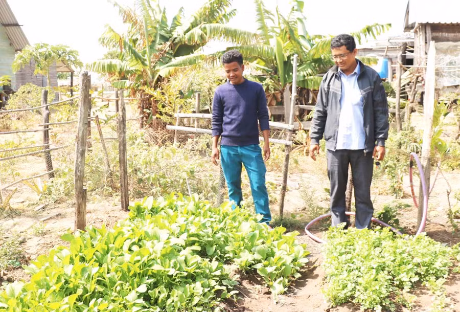 Anh Đinh Byei (bên trái) cải tạo đất vườn của gia đình trồng rau để bà con trong làng học hỏi làm theo. Ảnh: Nhật Hào