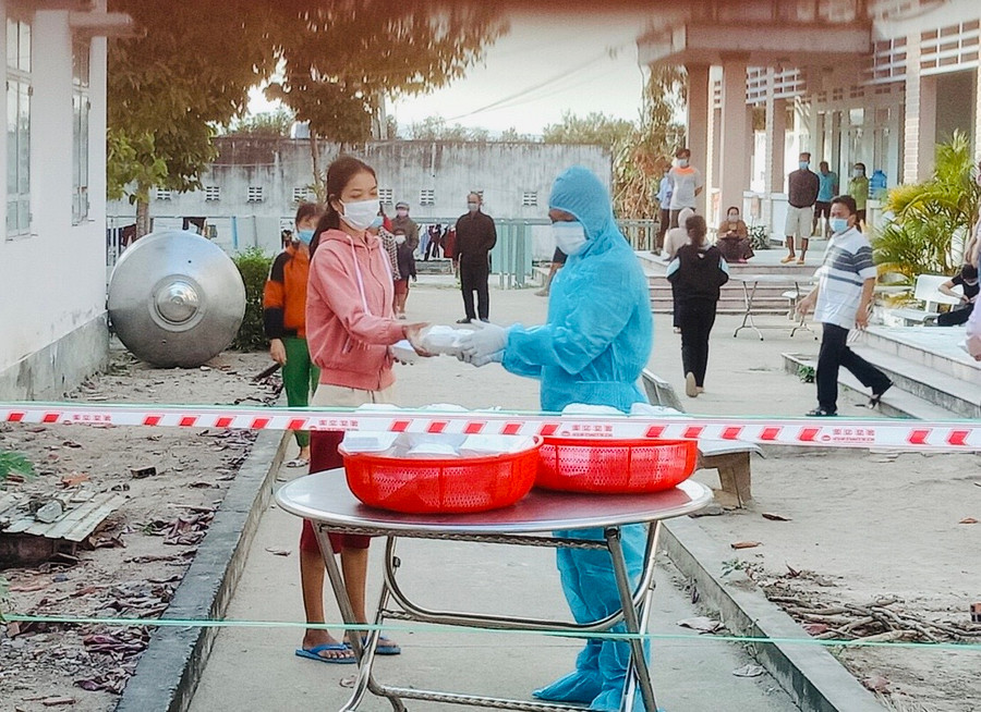 Tình nguyện viên trao các suất cơm cho người dân đang cách ly tại Trường THCS Dân tộc Nội trú huyện Ia Pa. Ảnh: Phan Lài