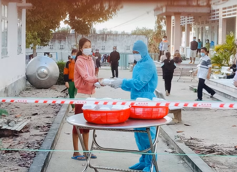 Tình nguyện viên trao các suất cơm cho người dân đang cách ly tại Trường THCS Dân tộc Nội trú huyện Ia Pa. Ảnh: Phan Lài