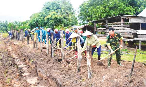 Cán bộ, chiến sĩ Trung đoàn Kinh tế-Quốc phòng 710, Binh đoàn 15 giúp nhân dân xã Ia Lâu (huyện Chư Prông) làm hàng rào. Ảnh: Vĩnh Hoàng
