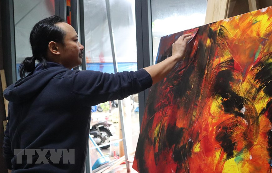 Họa sỹ Ngô Thanh Hùng sáng tác tranh tại nhà. (Ảnh: Văn Dũng/TTXVN)