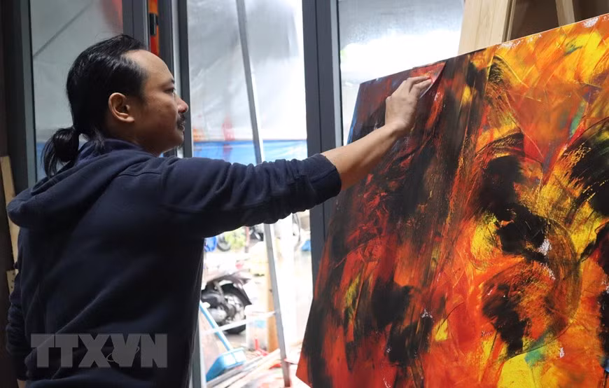 Họa sỹ Ngô Thanh Hùng sáng tác tranh tại nhà. (Ảnh: Văn Dũng/TTXVN)