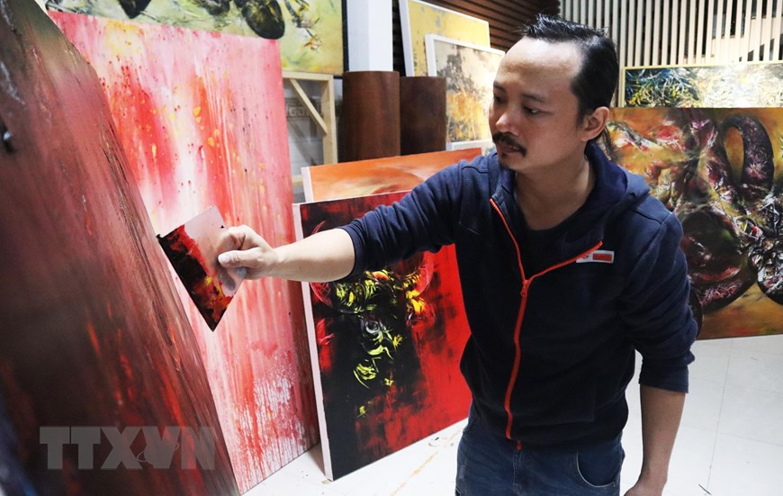 Họa sĩ Ngô Thanh Hùng sáng tác tranh tại nhà. (Ảnh: Văn Dũng/TTXVN)