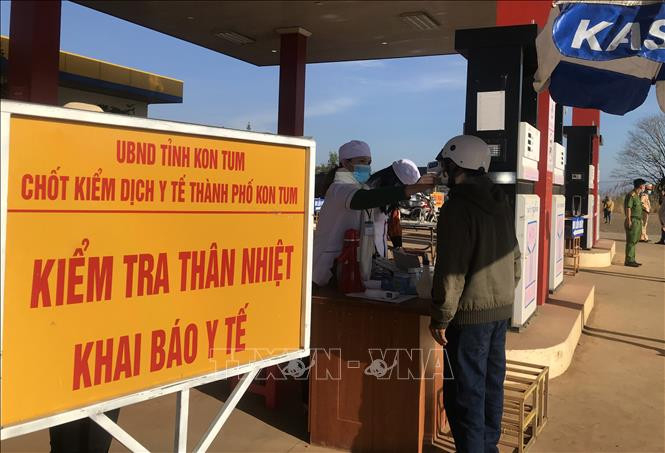 Người dân thực hiện đo thân nhiệt và khai báo y tế tại chốt kiểm soát dịch. Ảnh: Khoa Chương/TTXVN