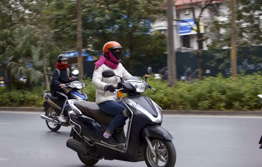 Người dân khi ra đường nên mặc ấm, đeo khẩu trang và mang theo áo mưa đề phòng những cơn mưa. (Ảnh: Tuấn Đức/TTXVN)