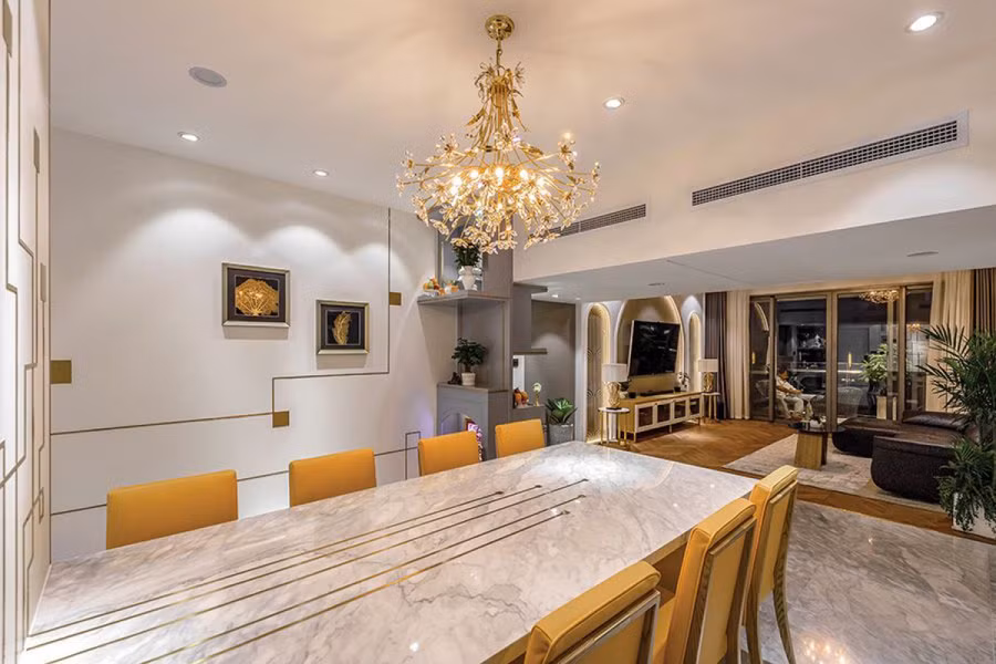 Khu vực bàn ăn được tạo điểm nhấn bằng bộ đèn chùm. Mặt bàn sử dụng chất liệu đá. Hầu hết các bề mặt như tường, mặt bàn, mặt tủ đều có những chi tiết trang trí sinh động.