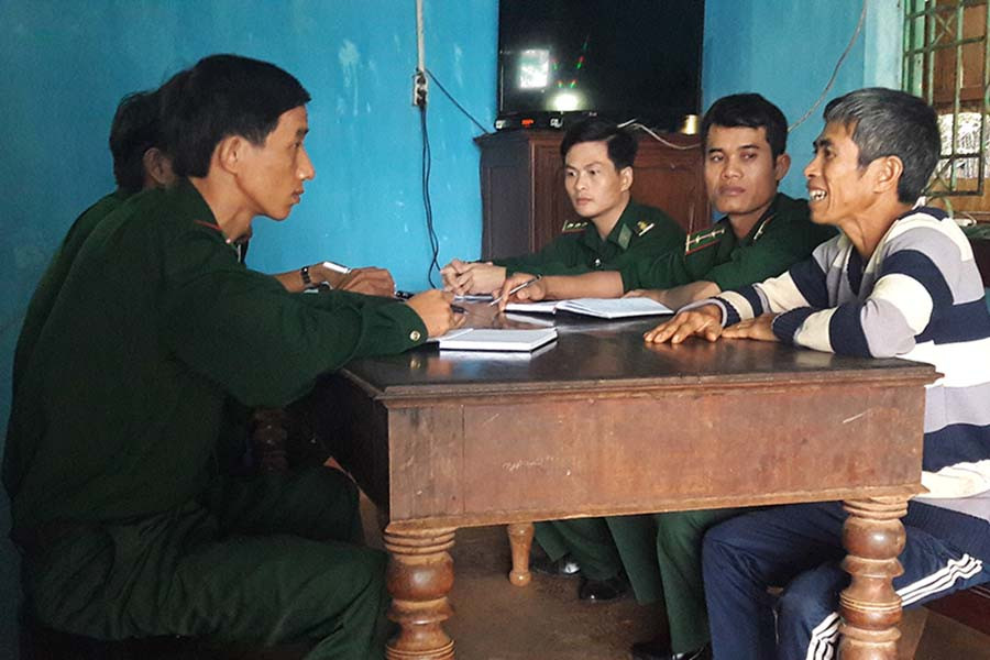  Trung úy Ngô Văn Hữu (ngoài cùng, bên trái) cùng cán bộ Đội công tác địa bàn đang trao đổi với trưởng nhóm đạo làng Nú, Rơ châm Miếu. Ảnh: A.H