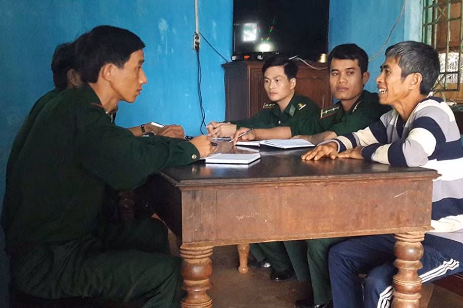  Trung úy Ngô Văn Hữu (ngoài cùng, bên trái) cùng cán bộ Đội công tác địa bàn đang trao đổi với trưởng nhóm đạo làng Nú, Rơ châm Miếu. Ảnh: A.H