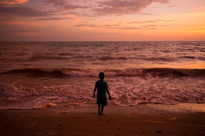 Cậu bé đứng trước bãi biển trong lúc hoàng hôn trên đảo Melville thuộc quần đảo Tiwi - Ảnh: DAVID MAURICE SMITH, OCULI/NG