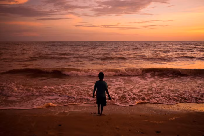 Cậu bé đứng trước bãi biển trong lúc hoàng hôn trên đảo Melville thuộc quần đảo Tiwi - Ảnh: DAVID MAURICE SMITH, OCULI/NG