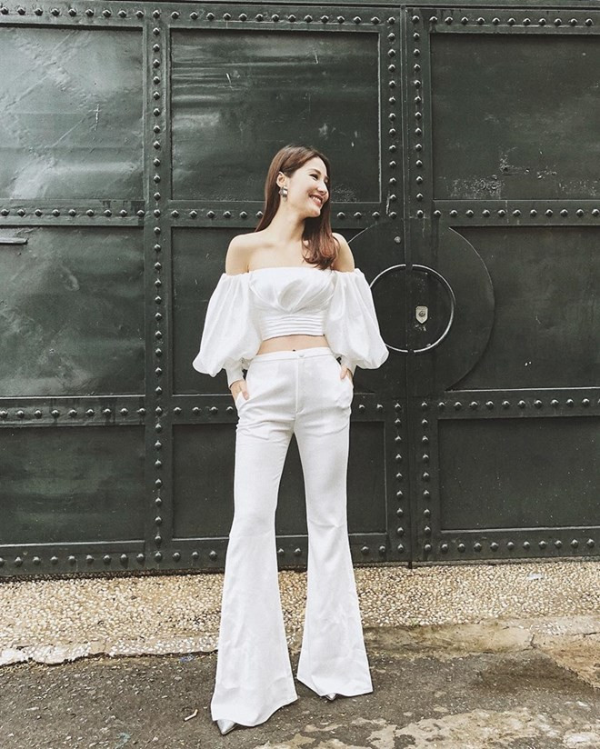 Cũng là tín đồ của quần ống loe, Diễm My 9X lại ghi điểm tuyệt đối nhờ mix mẫu quần tuyền trắng với crop top tay phồng ton-sur-ton, không chỉ để lộ vai trần mà còn phô diễn vòng eo gợi cảm.