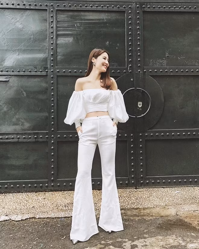 Cũng là tín đồ của quần ống loe, Diễm My 9X lại ghi điểm tuyệt đối nhờ mix mẫu quần tuyền trắng với crop top tay phồng ton-sur-ton, không chỉ để lộ vai trần mà còn phô diễn vòng eo gợi cảm.