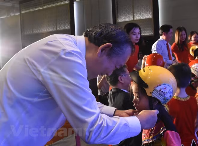 Phó Thủ tướng Chính phủ Trương Hòa Bình trao tặng mũ bảo hiểm cho học sinh lớp Một. 