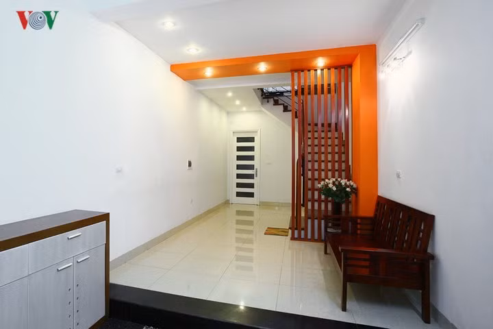 Không gian tầng trệt của một ngôi nhà phố có bề ngang hẹp. Không gian này được thiết kế là một phòng khách tạm, bởi phòng sinh hoạt chung ở trên lầu. Thực tế nơi này rất ít sử dụng nên chủ nhà chỉ kê một chiếc ghế dài áp tường - thay vì một bộ bàn ghế đầy đủ, để không gian thoáng rộng và tiện dụng cho việc đi lại.