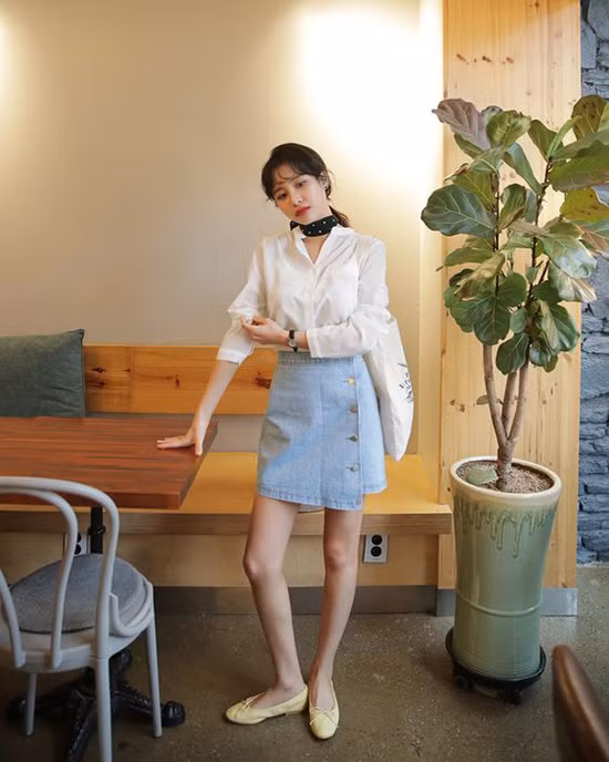 Đi cùng kiểu áo cài nút thông dụng là chân váy jeans vạt xéo, khăn turban, giày búp bê và túi tote.