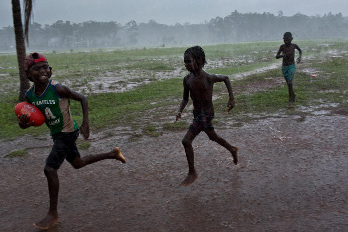 Một nhóm trẻ em chơi môn bóng đá kiểu Úc trong mưa tại khu dân cư Pirlangimpi, đảo Melville - Ảnh: DAVID MAURICE SMITH, OCULI/NG