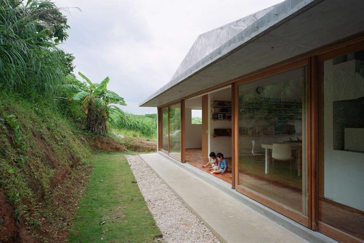  Mặt sau nhà thiết kế dựa vào lưng đồi, mái hiên rộng làm sân chơi cho những đứa trẻ.