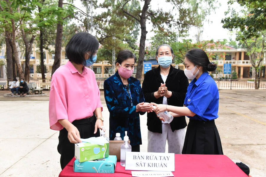 Đoàn viên thanh niên phường Hòa Lư hướng dẫn sát khuẩn trước khi vào nơi bỏ phiếu. Ảnh: Đức Thụy