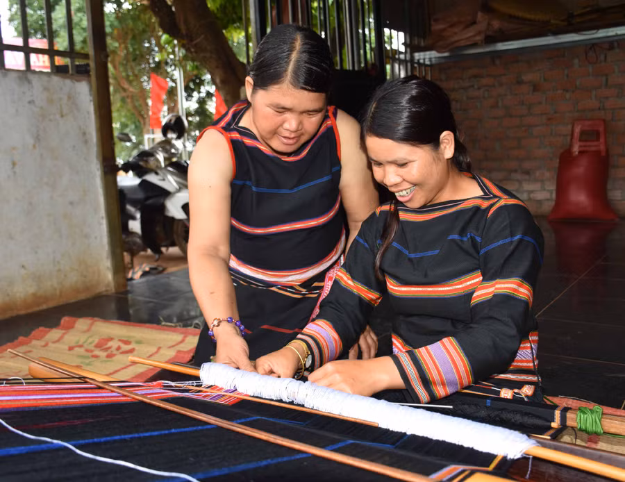 Mẹ con bà H’Yưt bên khung dệt. Ảnh: Trần Dung
