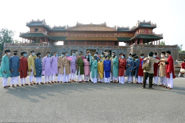 Du khách mặc áo dài truyền thống, đeo khẩu trang phòng dịch chụp ảnh trước cửa Ngọ Môn, Kinh thành Huế. (Ảnh: Đỗ Trưởng/TTXVN)