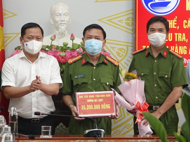 Chủ tịch UBND tỉnh Bình Định Nguyễn Phi Long (bìa trái) trao thưởng cho lực lượng công an tham gia phá vụ án trộm vàng. ẢNH: HOÀNG TRỌNG