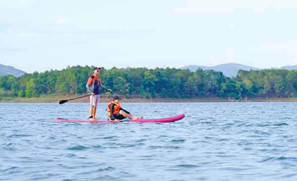 Chèo sup trên Biển Hồ cùng lúc ngắm được rừng thông xanh và dãy Chư Nâm hùng vĩ phía xa. Ảnh: Hoàng Ngọc