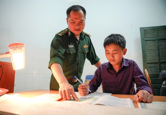Trung úy Nguyễn Quốc Hiệp đang hướng dẫn Sùng A Tủ học ở Đồn Biên phòng Trịnh Tường. Ảnh GIA KHÁNH