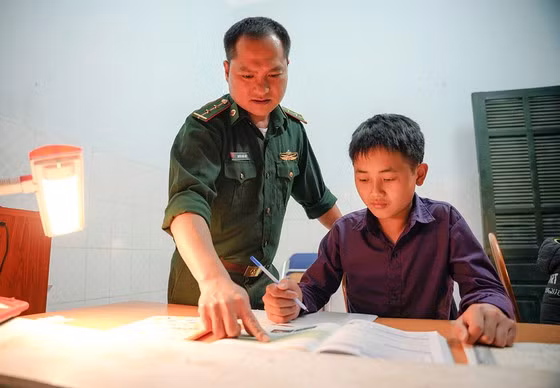 Trung úy Nguyễn Quốc Hiệp đang hướng dẫn Sùng A Tủ học ở Đồn Biên phòng Trịnh Tường. Ảnh GIA KHÁNH