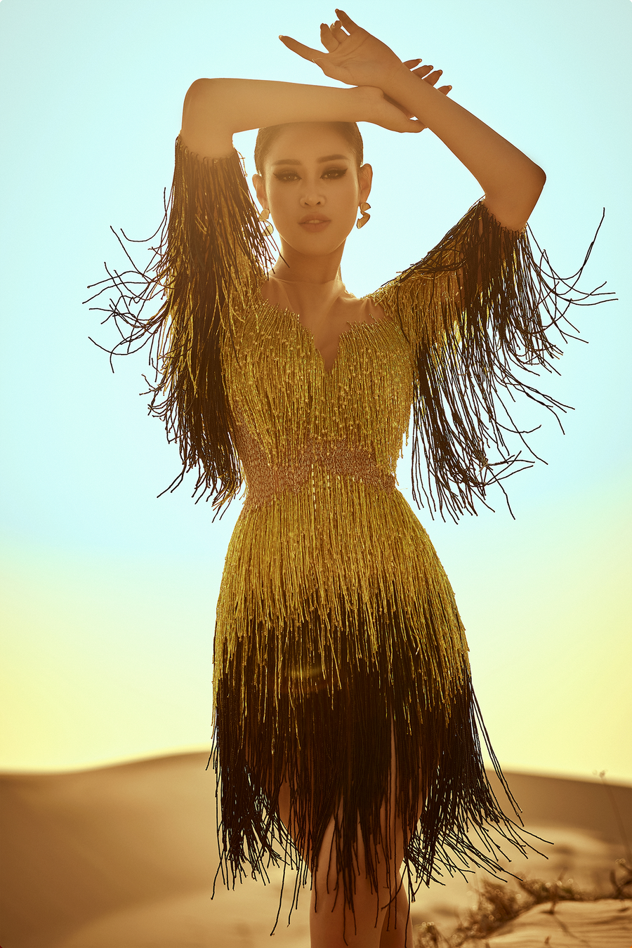 Trong trang phục đầm tua rua màu sắc rực rỡ, Khánh Vân nổi bật giữa đồi cát vào lúc bình minh, hoà quyện với khung cảnh tạo nên một bố cục hài hoà. Ảnh: Nguyễn Long.