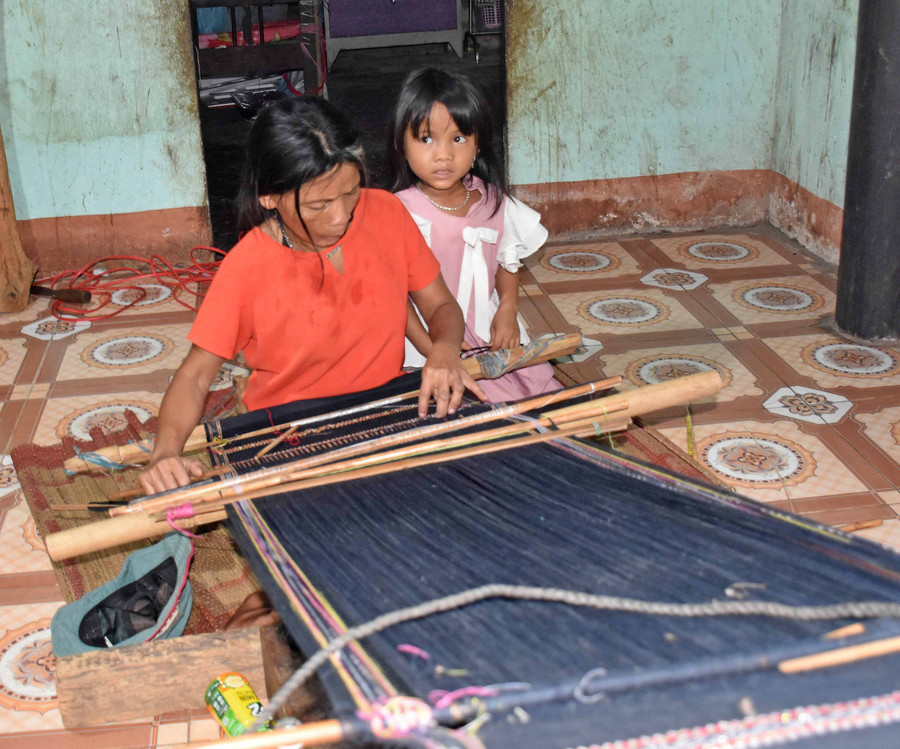 Chị Đinh Thị Hme cùng con gái bên khung dệt trong căn nhà của mình. Ảnh: Hà Phương