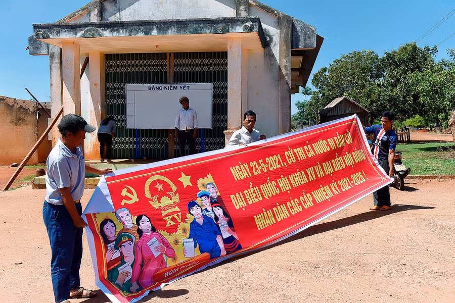 Người có uy tín ở xã Đăk Trôi, huyện Mang Yang tham gia treo các tấm băng rôn, pa nô tuyên truyền về bầu cử.