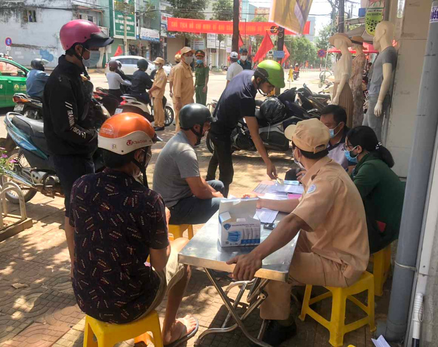 Lực lượng chức năng phường Hội Thương (TP. Pleiku) lập biên bản xử phạt hành chính người dân không đeo khẩu trang nơi công cộng. Ảnh: Hồ Anh Tiến