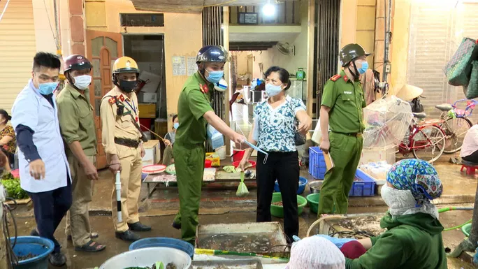 Lực lượng chức năng cấp phát khẩu trang cho các tiểu thương tại chợ Nê để phòng chống dịch bệnh Covid-19