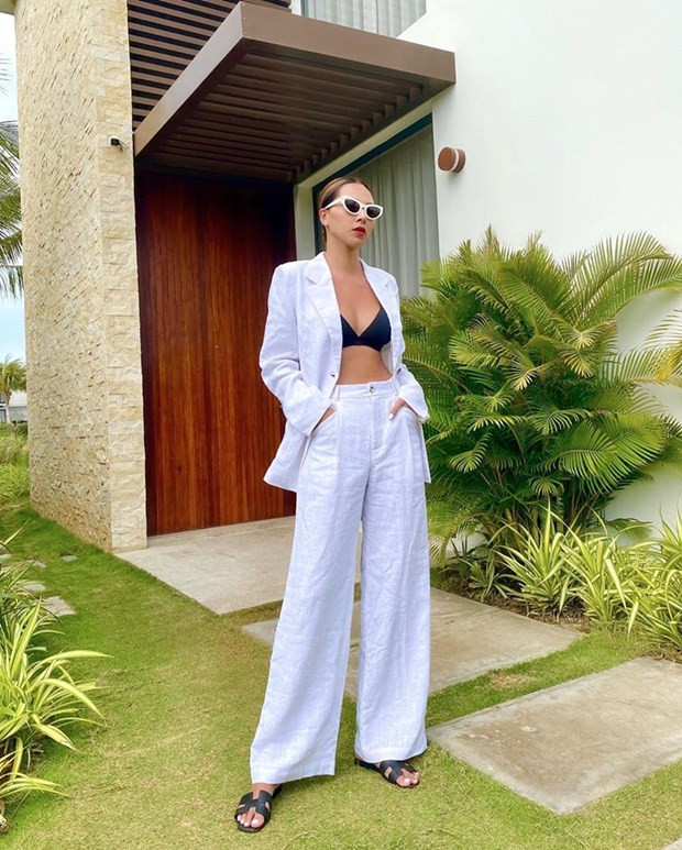 ''Đụng hàng'' Kỳ Duyên, Minh Triệu cũng chưng diện bộ đồ trắng giống cô bạn thân thiết. Tuy nhiên, siêu mẫu chơi trội bằng cách mix theo công thức khoe nội y. Chỉ với thao tác thả cúc, Minh Triệu đã tôn được body quyến rũ mà vẫn sành điệu hết tầm.