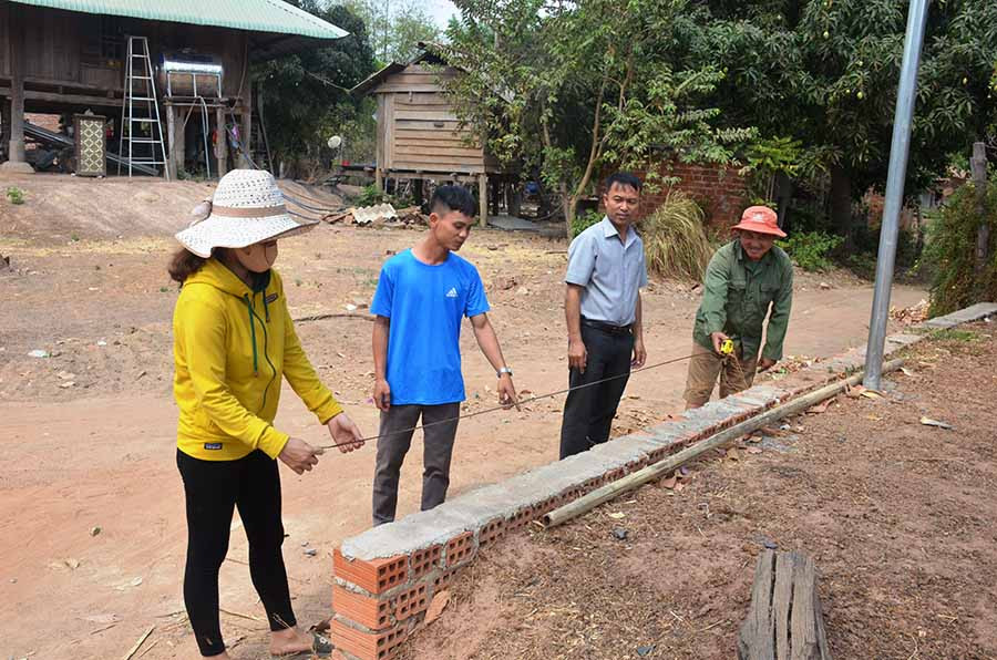 Anh Xa Văn Hoan (thứ 2 từ trái sang) đang cùng cán bộ thôn đo đạc đất trước khi đập bỏ bức tường để hiến hơn 200 m2 đất mở đường. Ảnh: V.H