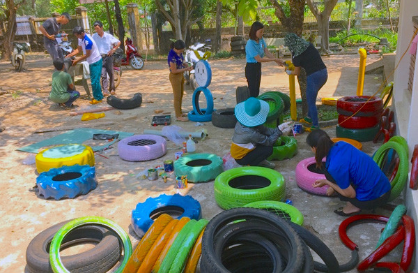 Các giáo viên Trường Tiểu học và THCS Nguyễn Du và đoàn viên, thanh niên xã Dun (huyện Chư Sê) sơn sửa lốp xe cũ để làm khu vui chơi cho học sinh. Ảnh: M.T