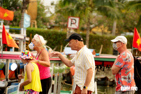 Nhóm du khách gồm 4 người thì 2 trong số này không đeo khẩu trang khi tham quan phố cổ - Ảnh: B.D.