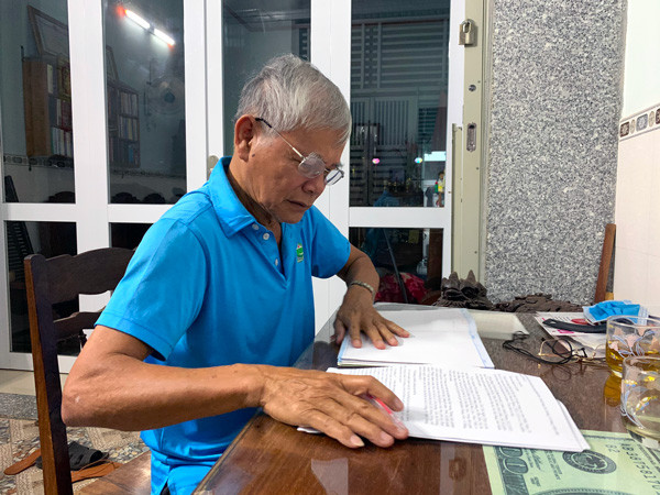 Ông Trần Chín ghi chép lại những tư liệu từ khi còn trong Nhà lao Pleiku để kể lại cho khách đến tham quan. Ảnh: P.L