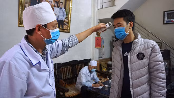  Đo thân nhiệt cho người đang cách ly tại gia đình ở P.Đông Hương, TP.Thanh Hóa -Ảnh: Minh Hải