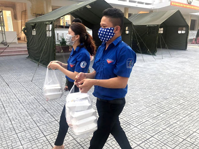 Thanh niên tình nguyện đưa khẩu phần ăn đến những người cách ly tại Trường Quân sự tỉnh Thừa Thiên- Huế. Ảnh: Lê Phương