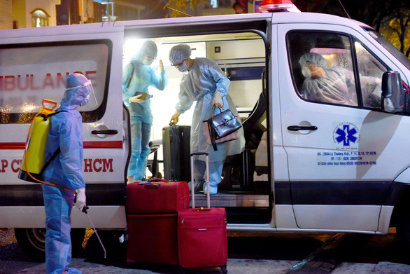 Sau khi được đưa từ khu cách ly ký túc xá khu A Đại học Quốc gia TP.HCM về Bệnh viện quận Bình Thạnh đêm 22-3, người nghi nhiễm được khử khuẩn từ khi bước xuống xe - Ảnh: DUYÊN PHAN