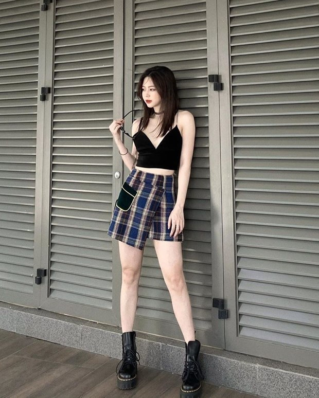 Liz Kim Cương biến tấu chân váy kẻ hơi hướng preppy bằng cách mix cùng crop top và boots.