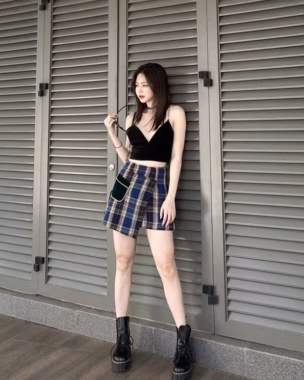 Liz Kim Cương biến tấu chân váy kẻ hơi hướng preppy bằng cách mix cùng crop top và boots.