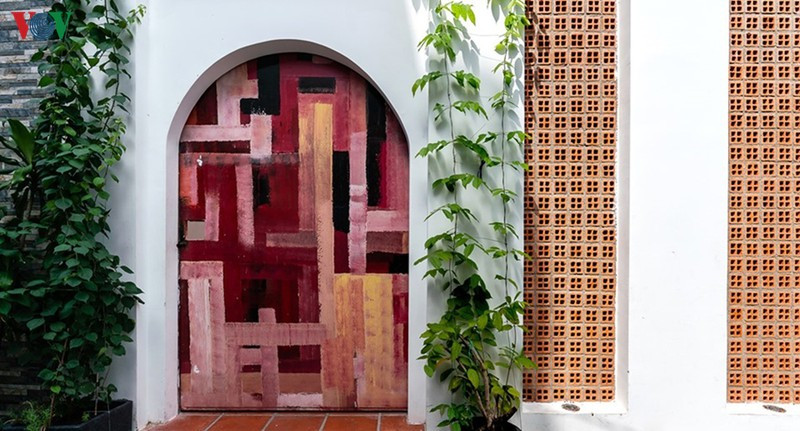 Cánh cổng bằng gỗ khi đóng lại như một bức tranh theo trường phái siêu thực. Những chậu cây nhỏ làm duyên cho lối vào.