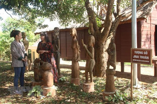 Thạc sỹ Hoàng Thanh Hương (phải) giới thiệu về khu tượng gỗ dân gian được trưng bày tại nhà rông làng Ốp, thành phố Pleiku. (Nguồn: TTXVN)