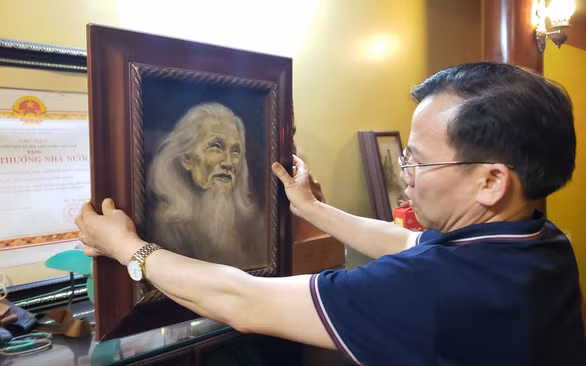 Con trai út và chân dung người cha Hữu Loan cùng bằng công nhận Giải thưởng Nhà nước về văn học nghệ thuật - Ảnh: THÁI LỘC