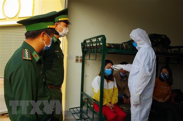 Cán bộ chiến sỹ Trạm kiểm soát Biên phòng Cửa khẩu Quốc tế Tây Trang phối hợp với cán bộ y tế đo thân nhiệt các công dân từ nước ngoài trở về. (Ảnh: Phan Tuấn Anh/TTXVN)