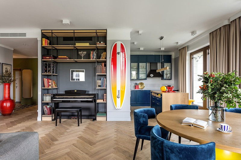 Giá sách ôm trọn đàn piano trong phòng khách, cạnh đó là ván lướt sóng treo tường nhằm phục vụ mục đích giải trí.