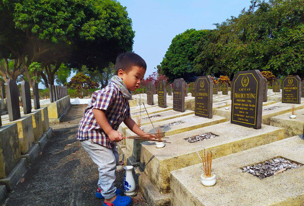 Đưa con đến nghĩa trang liệt sĩ thắp hương là một cách giáo dục truyền thống. Ảnh: T.N.Đ