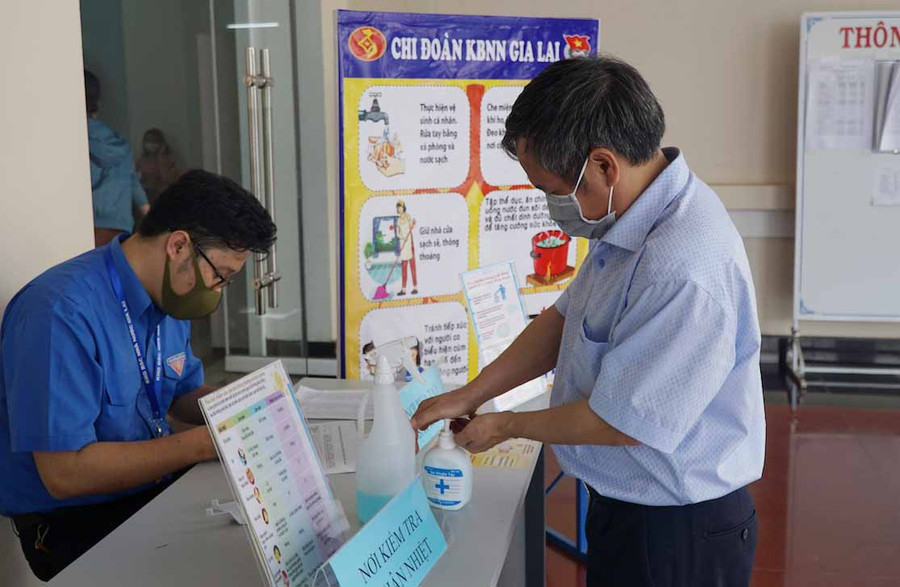 Tất cả các khách đến liên hệ công việc tại Kho bạc nhà nước đều phải đo thân nhiệt, rửa tay sát khuẩn và deo khẩu trang. Ảnh: Hà Duy